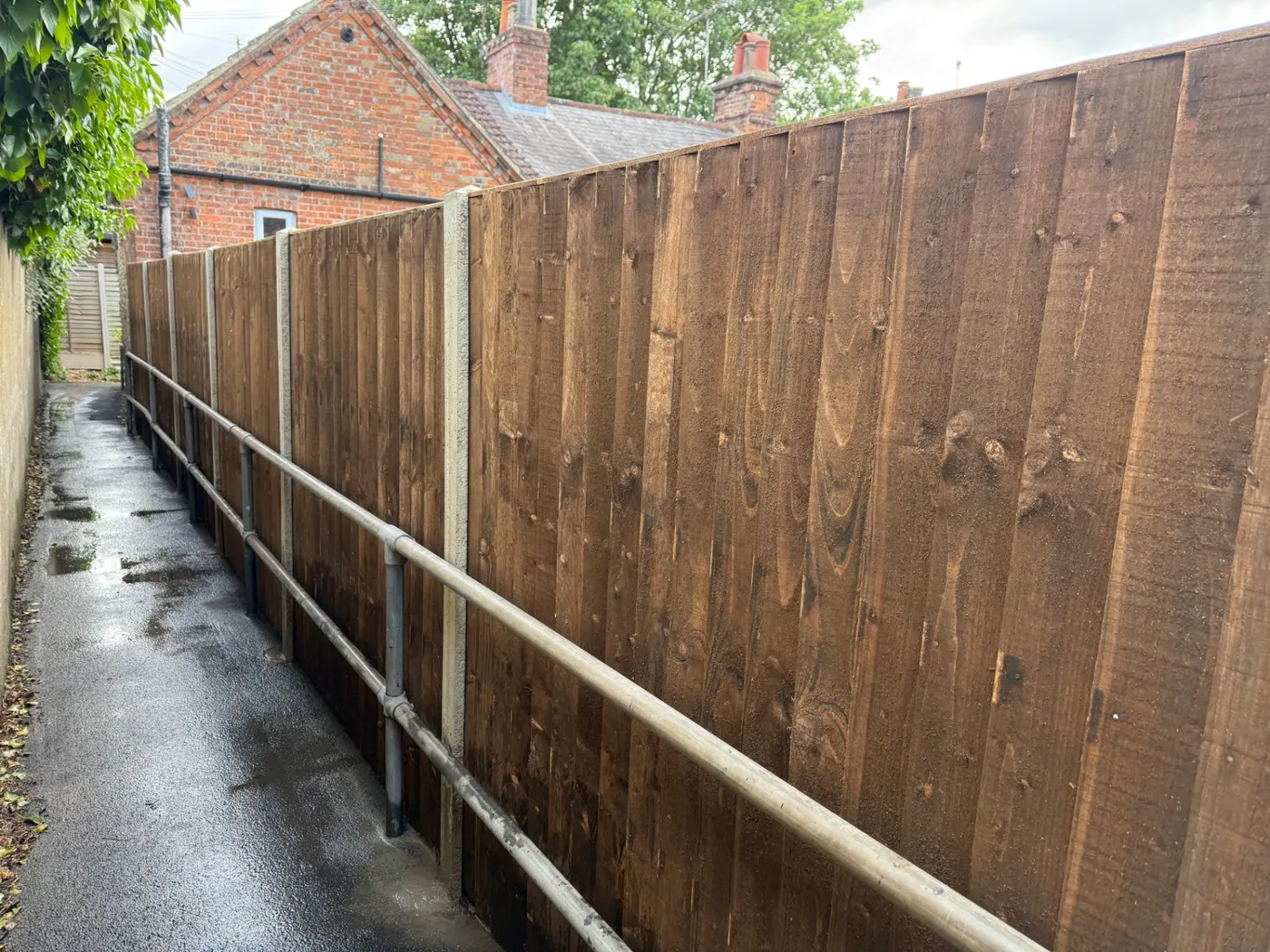 Tall closeboard boundary fence along a residential access lane