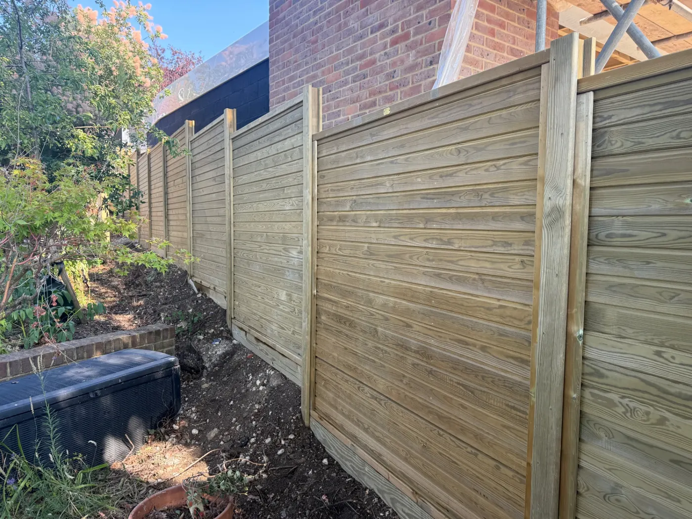 New horizontal slatted fence line beside a brick house